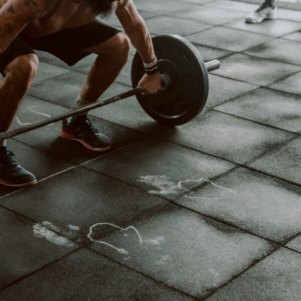 Hombre de rodillas levantando una barra con peso en el gimnasio