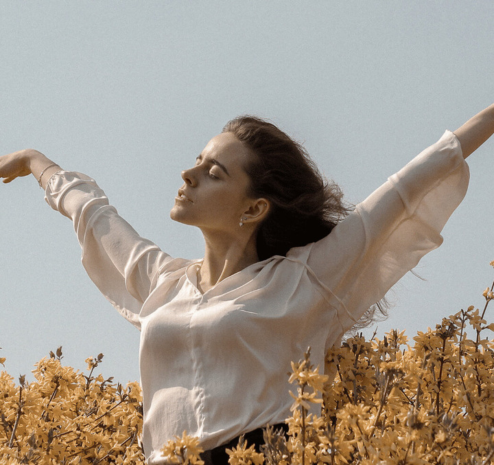 A woman opening her arms aganist the wind in flowers fields