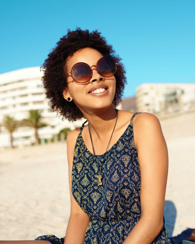 Mujer con gafas de sol sentada en una playa